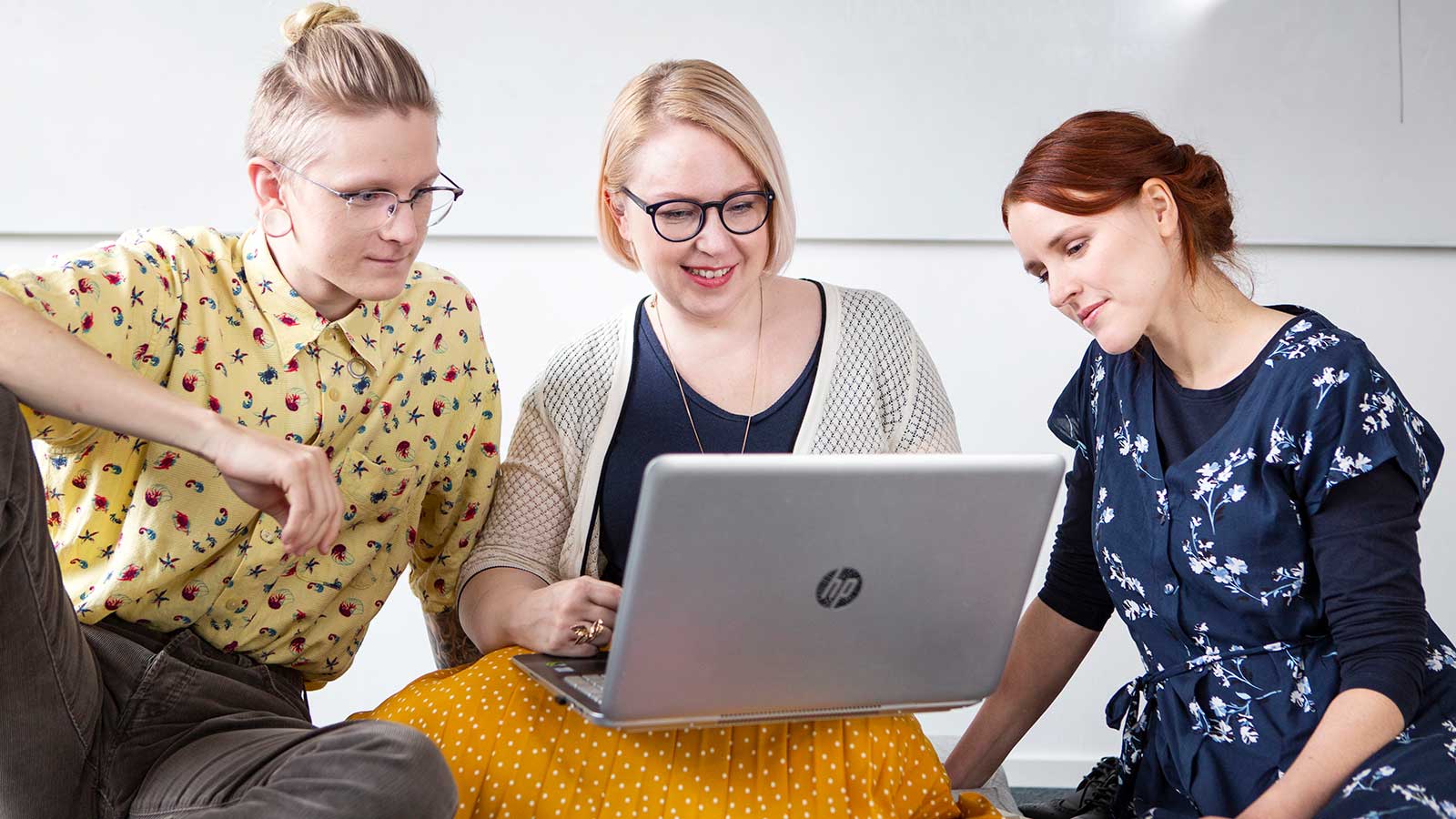 Kolme opiskelijaa kannettavan tietokoneen äärellä.
