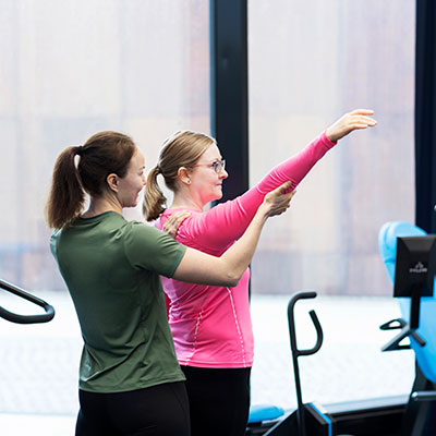 Physiotherapist is guiding a customer in the gym.