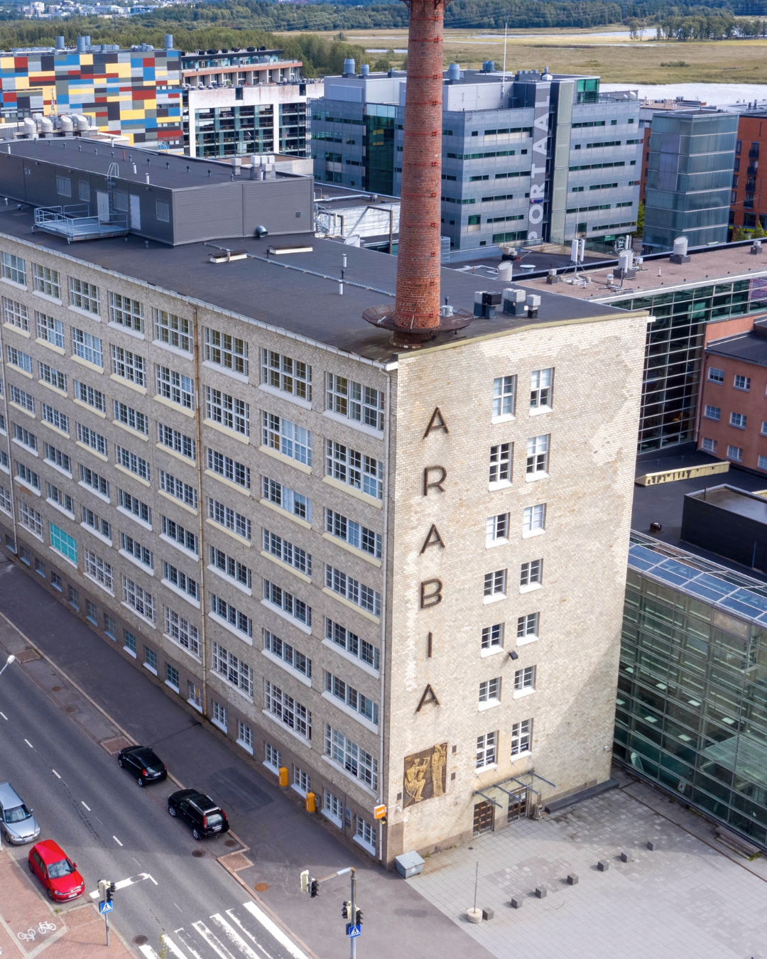 Arabian luova kampus kuvattuna ylhäältä. Edustalla näkyy Arabian tehdasrakennus ja taustalla asuintaloja, metsää ja merimaisema.