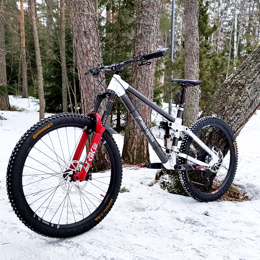 Polkupyörä nojaa puun runkoon talvisessa metsässä.
