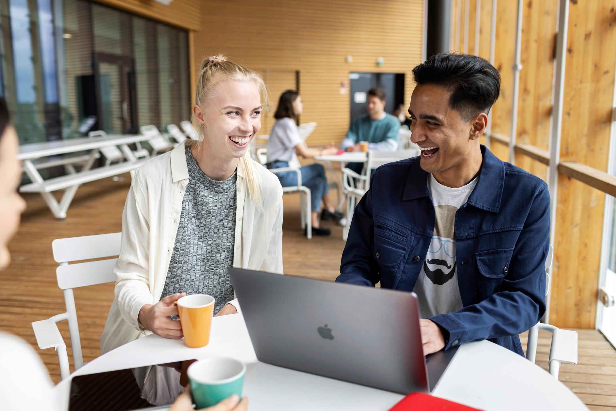 Students laughing and drinking coffee while studying