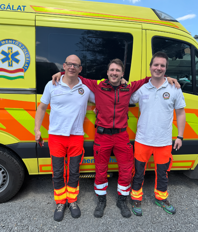 Opiskelijat poseeraavat ambulanssin edessä