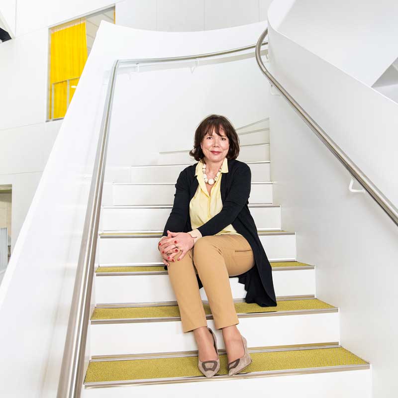 President and CEO Riitta Konkola sitting on the stairs in Myllypuro Campus.