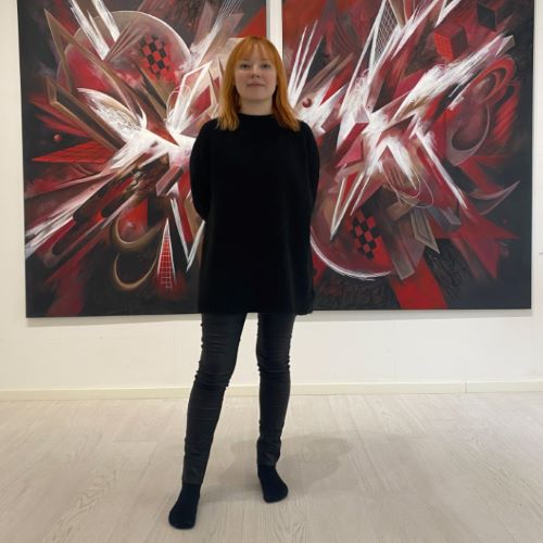 Muotoilun alumni Matilda Hööpakka mustissa vaatteissa kuvattuna punamustavalkoisen taideteoksen edessä.