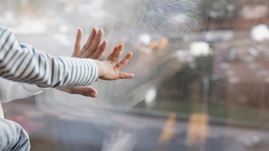 "The hand of a child and the hand of an adult touch the window.''