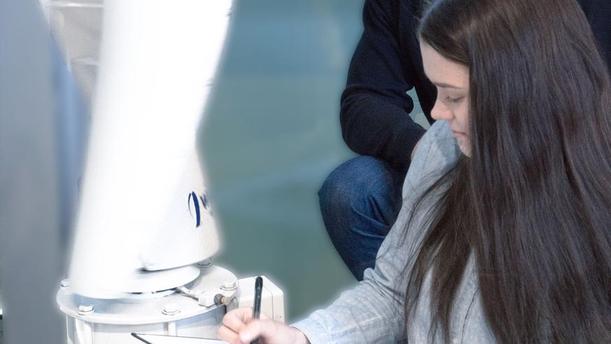 Opiskelija tekee muistiinpanoja energiatekniikan laboratoriossa.