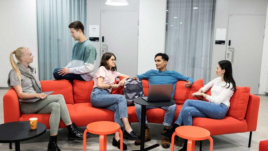 Five students discussing on the campus aile on a break.