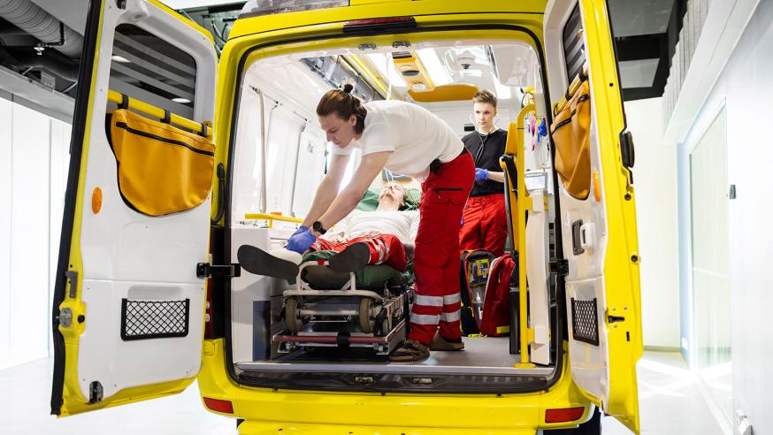 Kaksi opiskelijaa työskentelee ambulanssisimulaattorissa.