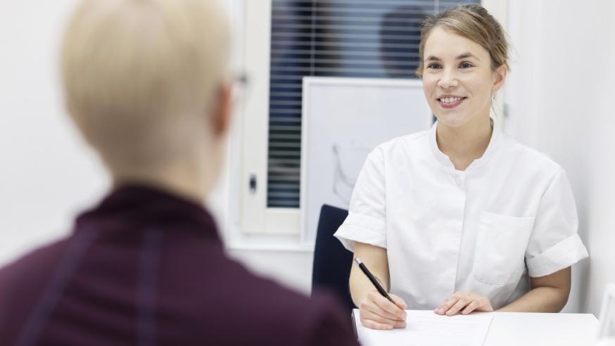 Seksuaaliterapeutti keskustelee asiakkaan kanssa pöydän ääressä.