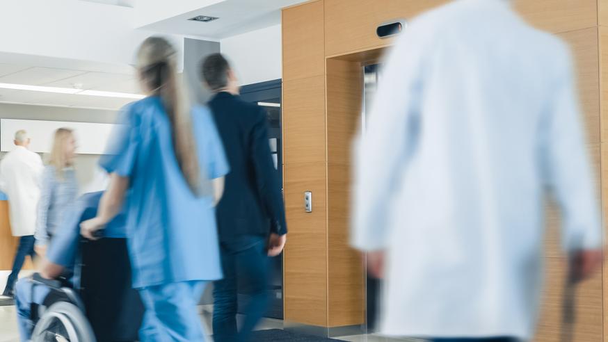 Hoitohenkilökuntaa ja asiakkaita sairaalan hissiaulassa.