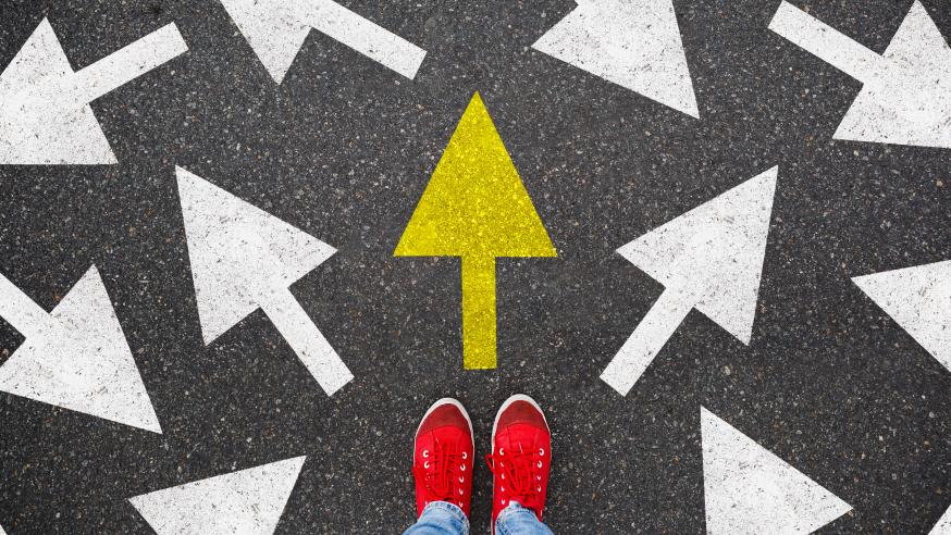 Henkilö seisoo asfalttiin maalattujen nuolten edessä.