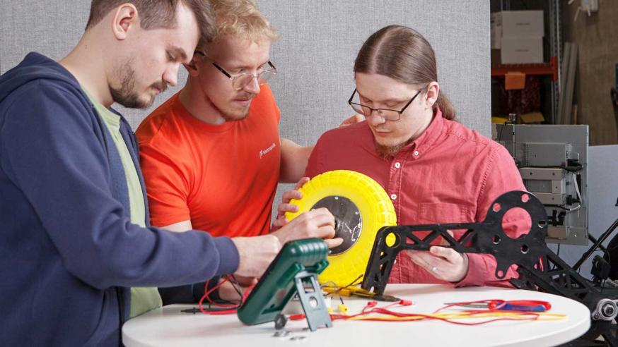 Three students building a robot.