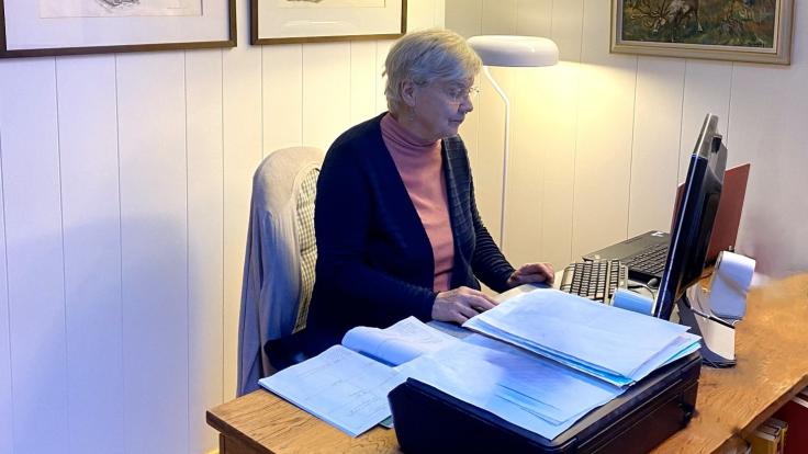 Ikääntynyt henkilö istuu tietokoneen ääressä.