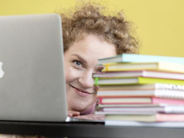 Smiling person with a computer and books.