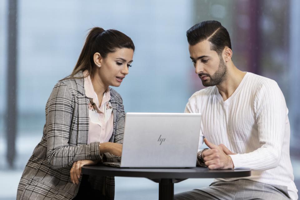 Two persons discussing and looking at the screen of a laptop.