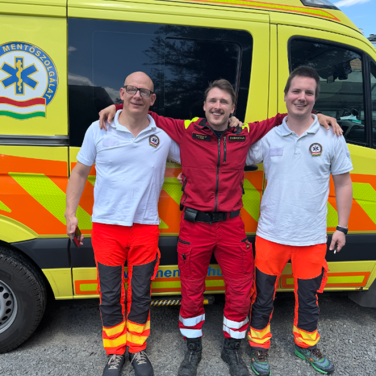 Opiskelijat poseeraavat ambulanssin edessä