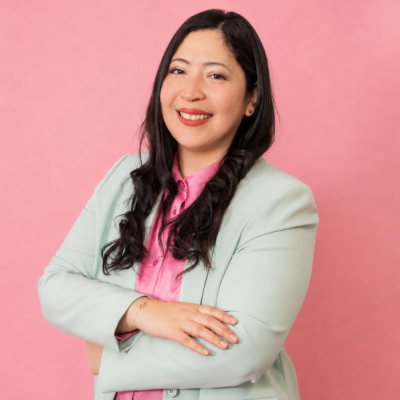Potretissa Kathia Saldana Valdez hymyilee vaaleassa takissa ja pinkissä kauluspaidassa, kädet ristissä rinnalla.