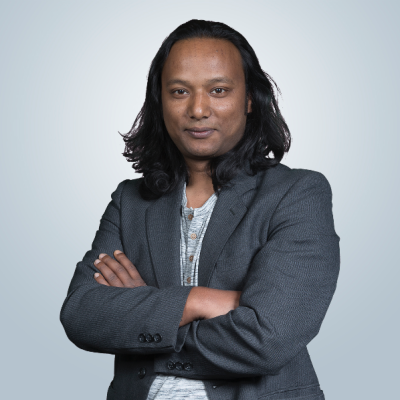 Potretissa Sunil Suwal hymyilee pikkutakissa, kädet ristissä rinnan päällä