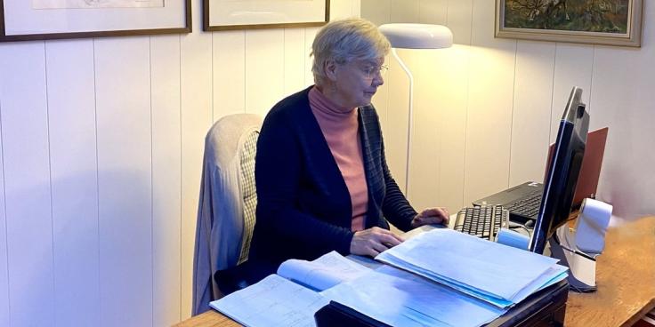 Nainen työskentelee tietokoneella työpöydän ääressä.