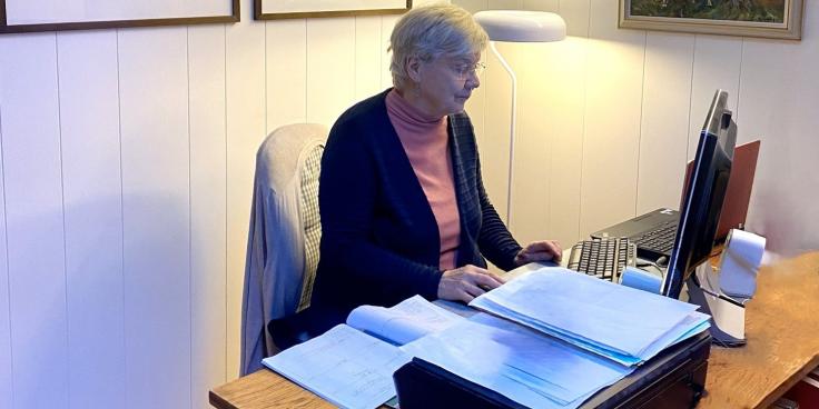 Ikääntynyt henkilö istuu tietokoneen ääressä.