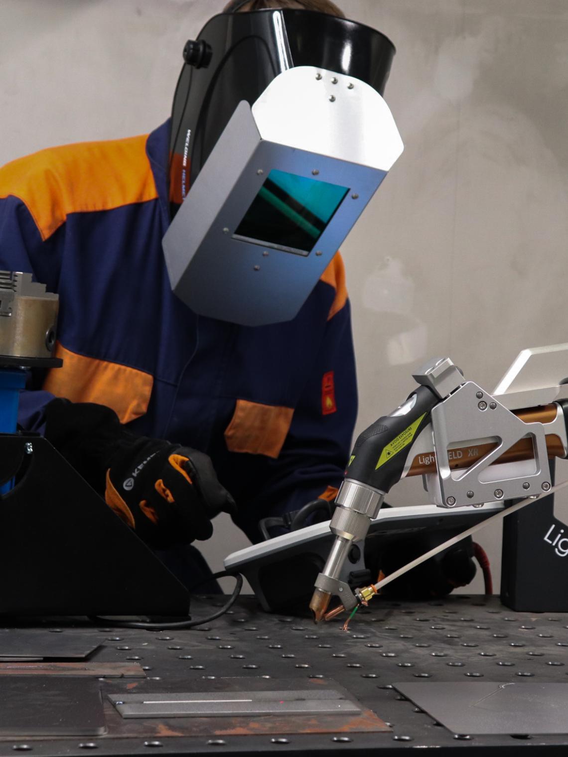 The person is operating a welding robot