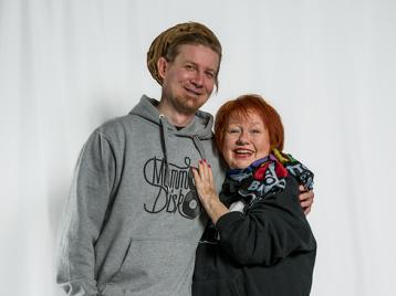 Kuvituskuva, jossa tilaisuuden juontajat Tuija ja Mikko seisovat ja hymyilevät vierekkäin.