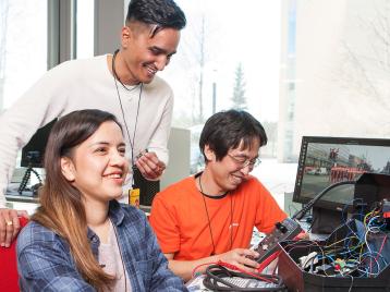 Kolme opiskelijaa työskentelee yhdessä IoT-laboratoriossa.
